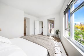 Denver apartment for rent - A bedroom with a large bed and a window overlooking a cityscape.