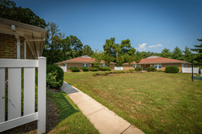 Waldorf apartment for rent - A white picket fence leads to a grassy area with three houses in the background.