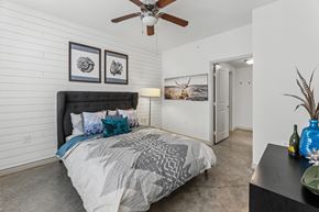 Austin apartment for rent - A bedroom with a bed, a ceiling fan, and a painting on the wall.