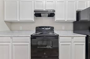 Denton apartment for rent - A black stove in a kitchen with white cabinets.