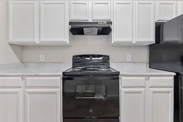 Denton apartment for rent - A black stove in a kitchen with white cabinets.