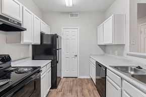 Denton apartment for rent - A kitchen with black appliances and white cabinets.