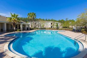 Jacksonville apartment for rent - Swimming Pool with Lounge Seating and Clubhouse in the Background