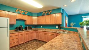 Hampton apartment for rent - Clubhouse kitchen area with granite style countertops, cabinets, wood style flooring and white refrigerator