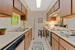 High Point apartment for rent - A kitchen with wooden cabinets and a black dishwasher at Fox Hollow Apartment Homes, High Point, NC