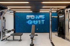 Key West apartment for rent - a gym with a blue neon sign on the wall and a gym chair