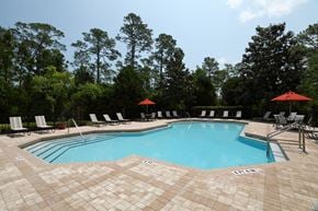 St. Augustine apartment for rent - The swimming pool is a large area with calm turquoise waters with a brick paver sundeck surrounding. Light lounge chairs and orange umbrellas are placed around the sundeck.