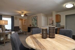 St. Augustine apartment for rent - The Dining Room table is shown in the foreground with dark chairs surrounding and decor on the tabletop. The kitchen is shown on the right side with the Living Room in the background on the left.