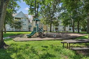 Waldorf apartment for rent - A playground with a green slide and picnic table in front of apartment buildings.