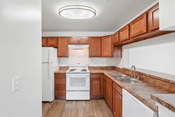 Fredericksburg apartment for rent - A kitchen with wooden cabinets and a white refrigerator.