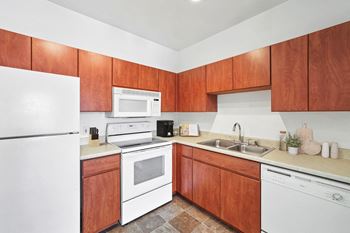 Apartment kitchen with white appliances and wood cabinetry