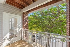 Waldorf apartment for rent - A balcony with a white railing and a view of a tree and a building.