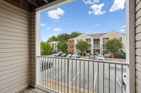 Fredericksburg apartment for rent - A view from a balcony looking out at a parking lot and apartment buildings.