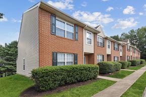 Stafford apartment for rent - A row of buildings with green bushes in front.