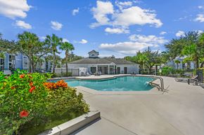 Orlando apartment for rent - Pool area with tanning chairs on the deck surrounded by natural landscaping