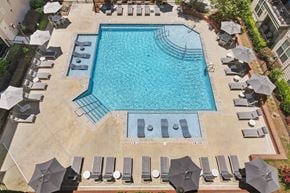 Kennesaw apartment for rent - An aerial view of a swimming pool surrounded by lounge chairs and umbrellas.