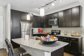 Kennesaw apartment for rent - A kitchen with black cabinets and a granite countertop.