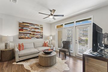 Kennesaw apartment for rent - A living room with a grey couch, a wooden coffee table, a flat screen TV and a painting on the wall.