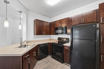 Waldorf apartment for rent - A kitchen with a black refrigerator and wooden cabinets.