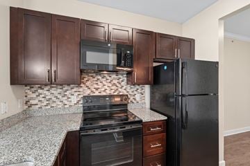 Waldorf apartment for rent - A kitchen with brown cabinets and a black refrigerator.