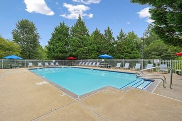 Fredericksburg apartment for rent - A large swimming pool surrounded by trees and chairs.