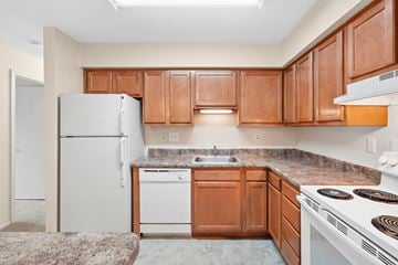 Waldorf apartment for rent - A kitchen with brown cabinets and a white refrigerator.