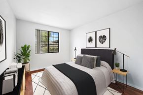 Phoenix apartment for rent - Bedroom with dark upholstered headboard and botanical prints at ReNue Downtown Apartments, Phoenix, AZ 85007