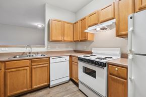 Denton apartment for rent - A kitchen with wooden cabinets and white appliances.