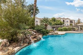 Mesa apartment for rent - Swimming pool with cascading waterfall and lush greenery at Tierra Antigua Apartments, Mesa, AZ 85207