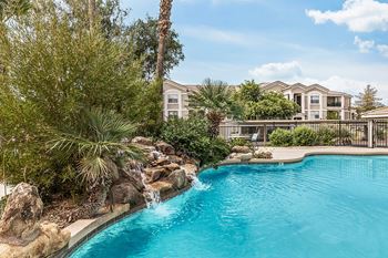 Pool with natural rock waterfall and tropical plants