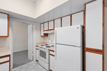 Waldorf apartment for rent - A white refrigerator is in a kitchen with a white oven and wooden cabinets.