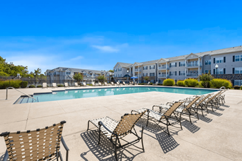 A pool surrounded by sun loungers and chairs.