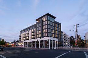 Oakland apartment for rent - A modern building with a black and white facade is illuminated by the setting sun.