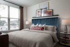 Fulshear apartment for rent - a bedroom with a large window and a large bed with a blue headboard