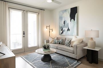 Brookshire apartment for rent - A living room with a grey couch, a coffee table, and a painting on the wall.