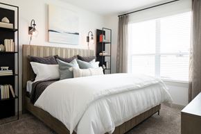 Brookshire apartment for rent - a bedroom with white walls and a large bed with a wooden headboard