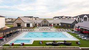 Brookshire apartment for rent - a large pool with lounge chairs in front of a building