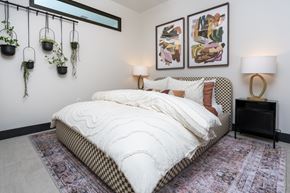 Denver apartment for rent - A bedroom with a large bed and two hanging potted plants.
