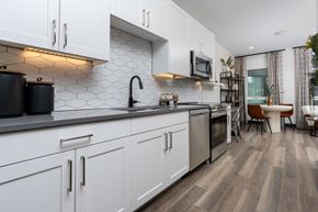Denver apartment for rent - A modern kitchen with white cabinets and a black countertop.