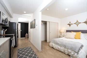 Seattle apartment for rent - A modern bedroom with a large bed and a kitchen area.
