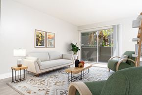 Anaheim apartment for rent - A living room with a white couch, a green chair, and a rug.