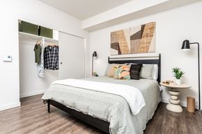 Redmond apartment for rent - A bedroom with a bed, a clothing rack, and a painting on the wall.