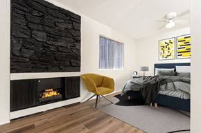 Los Angeles apartment for rent - A modern bedroom with a stone wall and a yellow chair.