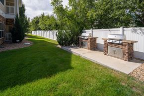 Arvada apartment for rent - A white fence surrounds a grassy area with two stone pillars in front.