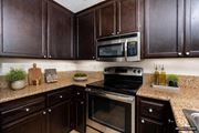 Cupertino apartment for rent - A kitchen with dark brown cabinets and a black stove top oven.