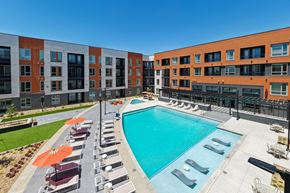 Aurora apartment for rent - A swimming pool surrounded by sun loungers and umbrellas in front of a building.