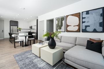 Aurora apartment for rent - A modern living room with a grey sofa, a white coffee table, and a dining table with chairs.