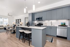 Livermore apartment for rent - a kitchen with an island and stools in front of a living room with a couch and