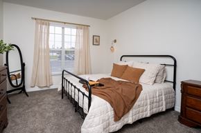 Rock Springs apartment for rent - A bedroom with a bed, nightstand, and window.