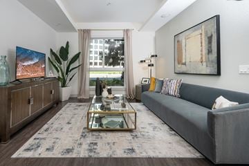 Irvine apartment for rent - A modern living room with a grey sofa, a glass coffee table, and a large painting on the wall.